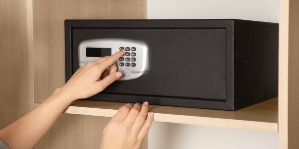 Woman opening black steel safe with electronic lock at hotel, closeup