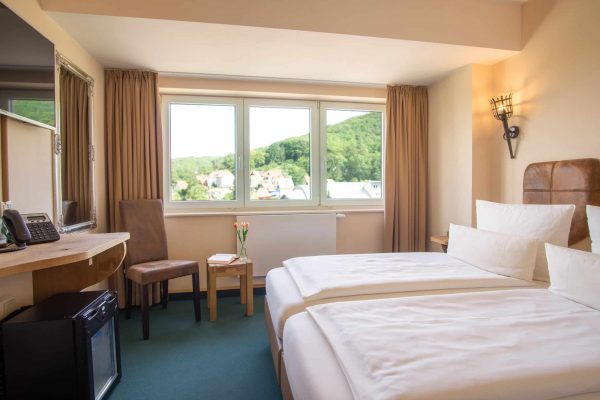 Separates Schlafzimmer mit Doppelbett und Stadtblick im Familienapartment des Hasseröder Burghotels Wernigerode